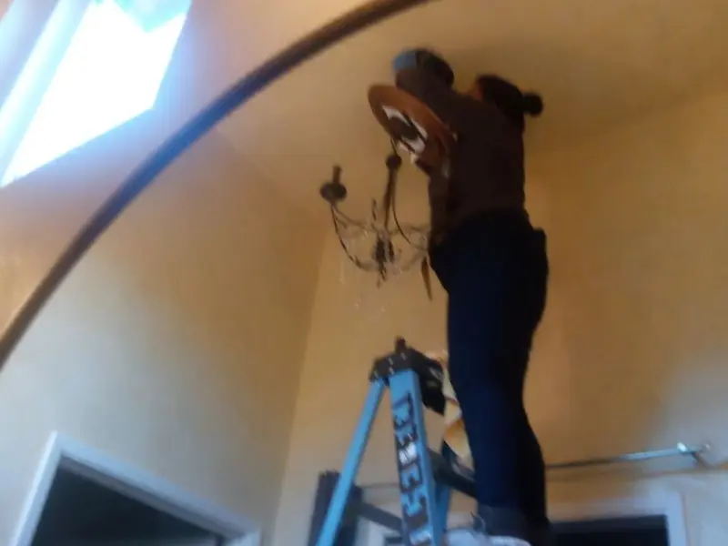 Electrician installing a chandelier in a Gonzalez residence